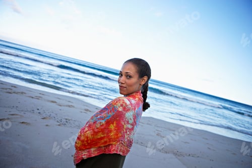 Preview: Angled Shot Of A Smiling Woman Wrapped In Shawl Standing On Beach During Sunset.