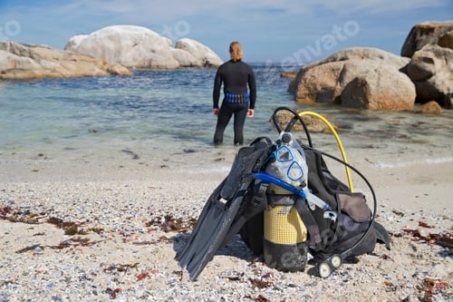 Preview: Close-Up Of Scuba Equipment On Beach With Diver In Ocean In Background