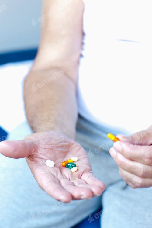 Preview: A Senior Man Holding An Assortment Of Tablets In His Hand