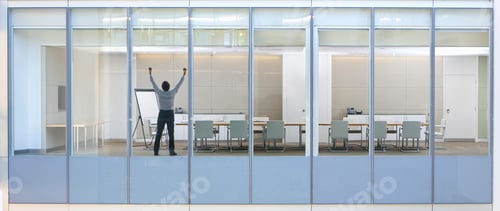 Preview: Wide Shot Through An Office Window With A Businessman Standing In The Meeting Room With His Arms