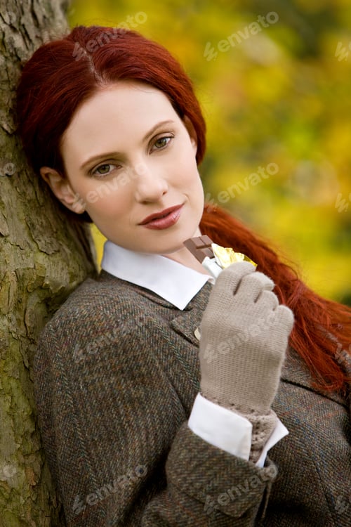 Preview: A Young Woman Leaning Against A Tree, Eating Chocolate