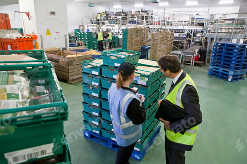 Preview: High Angle Shot Of A Supervisor And Worker Examining Stacked Containers At A Food Processing Plant