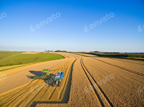 Preview: Aerial View Of Combine Harvester Filling Tractor Trailer In A Sunny Barley Field Under Blue Skies