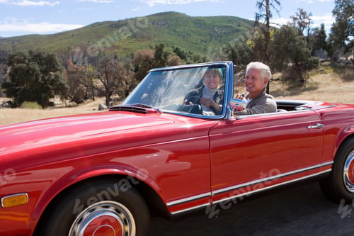Preview: Mature Couple Driving Classic Red Convertible Car On Road Trip