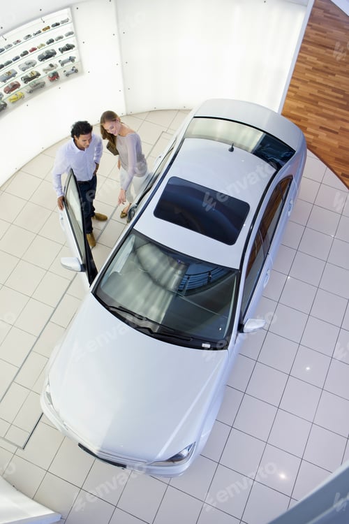 Preview: Couple Looking Inside Car In A Car Dealership Showroom