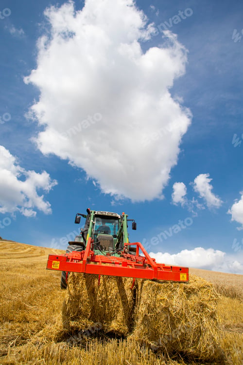 Preview: Vertical Shot Of A Tractor Arranging Straw Bales In A Rural Field On A Sunny Day.