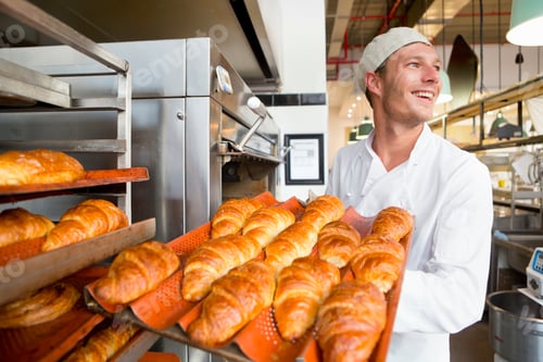 Preview: Smiling Baker Holding A Tray Of Bread In A Bakery Kitchen