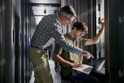 Preview: Two Technicians Working On A Laptop In The Secured Data Center
