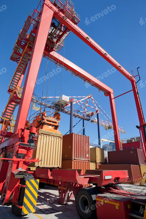 Vista previa: Low Angle Shot Of Gantry Cranes Loading Cargo Containers On Lorries In A Dockyard