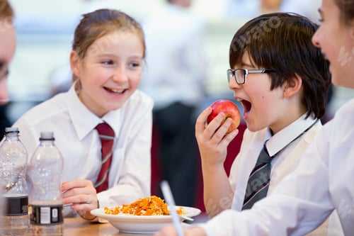 Preview: Side View Of A Middle School Students Eating An Apple During Lunch In The School Cafeteria.