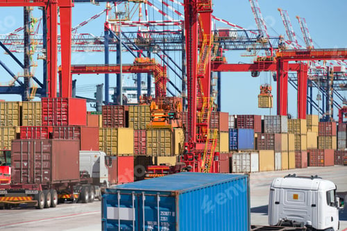 Preview: Trucks Carrying Cargo Containers Along The Pathway Of A Commercial Dock With Cranes.