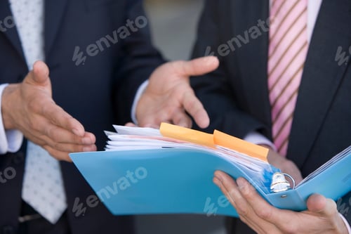 Preview: Detail Of Two Businessmen Discussing Document In File
