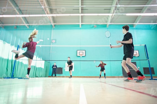 Preview: Low Angle Shot Of High School Students Playing Badminton During A Gym Class.