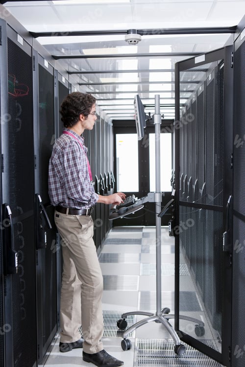 Preview: Vertical Shot Of A Young Technician Working On A Computer Connected To A Cabinet In The Server Room.