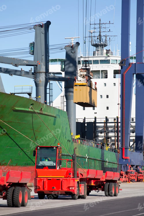 Preview: Vertical Shot Of A Crane Lifting A Cargo Container From A Truck Next To Ship At A Commercial Dock.