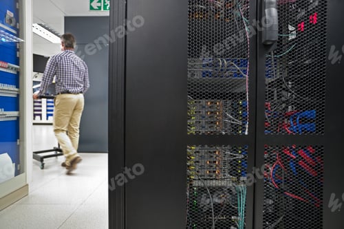 Preview: Back Shot Of A Technician Working On A Laptop In The Secured Data Center
