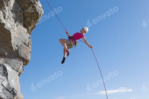 Preview: Wide Shot Of A Female Rock Climber Abseiling Down A Rock Face.