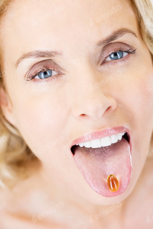 Preview: A Middle-Aged Woman With A Vitamin Supplement Capsule On Her Tongue