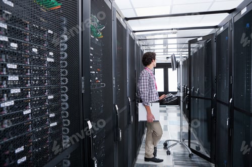 Preview: Wide Shot Of A Young Technician Working On A Computer Connected To A Cabinet In The Server Room.