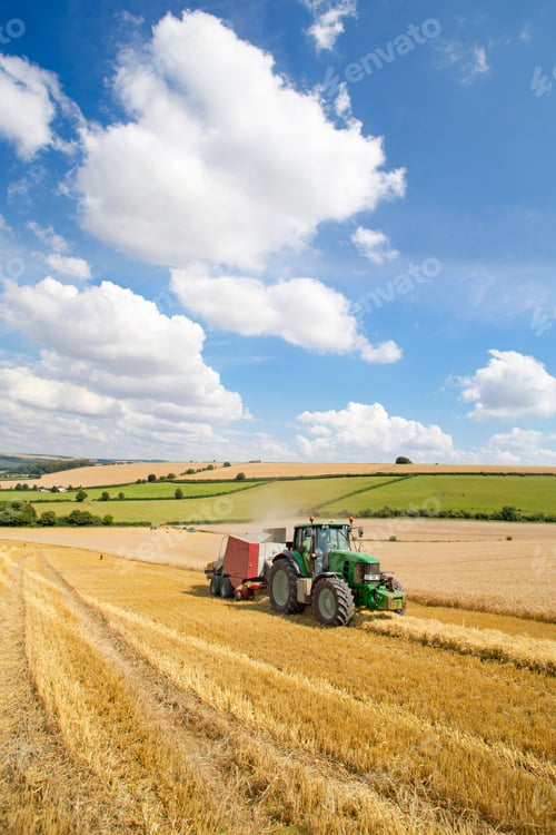 Preview: Vertical Wide Shot Of A Tractor Baling Straw Over A Rural Field On A Cloudy Day.