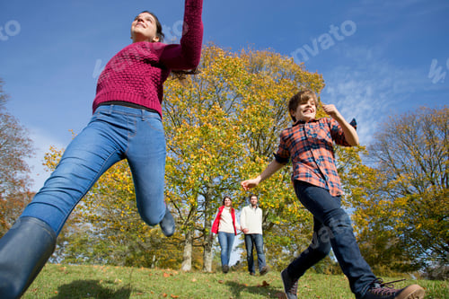 Preview: Children Running In An Autumnal Forest With Their Parents Holding Hands And Walking In The