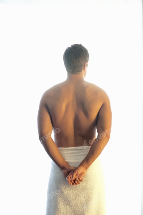 Preview: Backside Of A Man In Towel Standing Against A Bright Background.