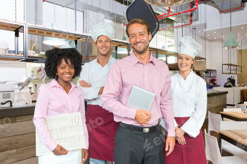 Preview: Bakery Owner Standing Holding A Digital Tablet With Bakers And Waitress In A Bakery