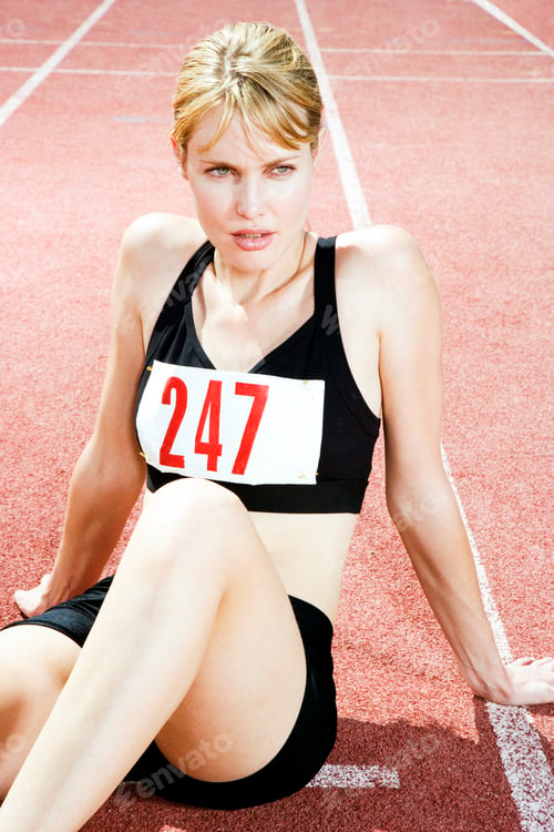 Preview: Portrait Of A Female Athlete Resting And Sitting On The Running Track