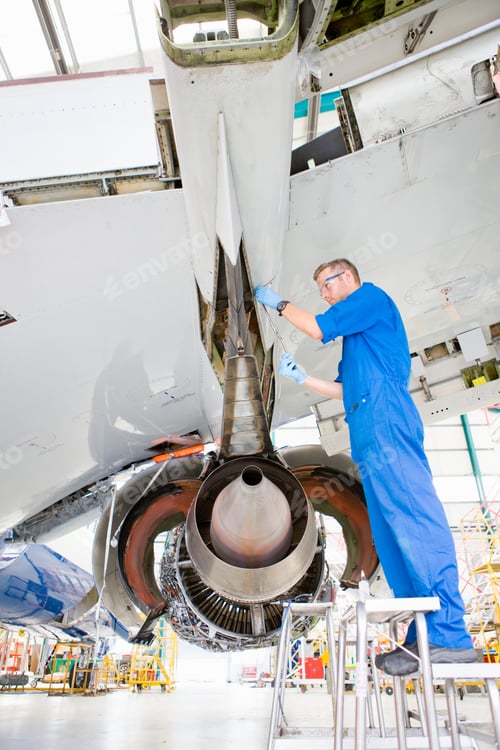 Preview: Low-Angle Vertical Shot Of An Engineer Working Under The Wing Of A Passenger Jet At A Hangar.