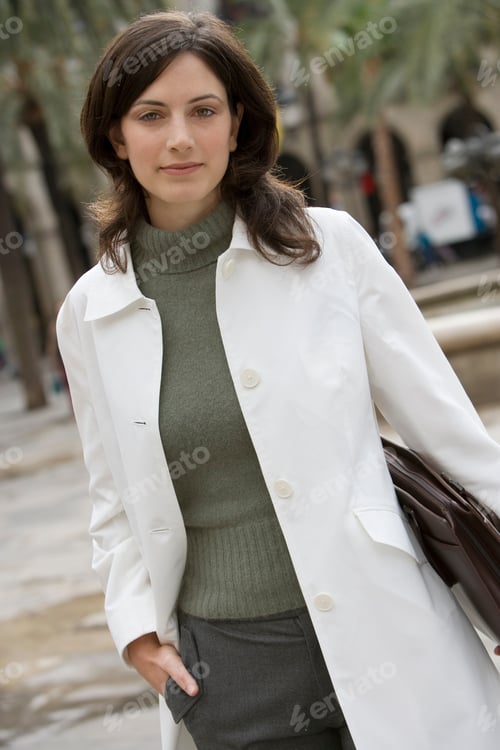 Preview: An Angled Mid Length Shot Of Businesswoman In Polo Neck Jumper And White Coat Walking In Plaza