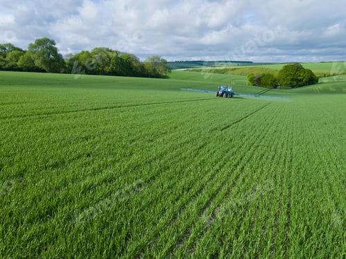 Preview: Tractor Spraying Crop In Green Farm Fields With Pesticide