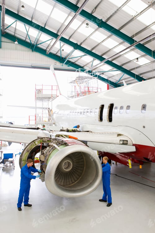 Preview: Vertical Wide Shot Of Engineers Assembling An Engine On A Passenger Jet At A Hangar.