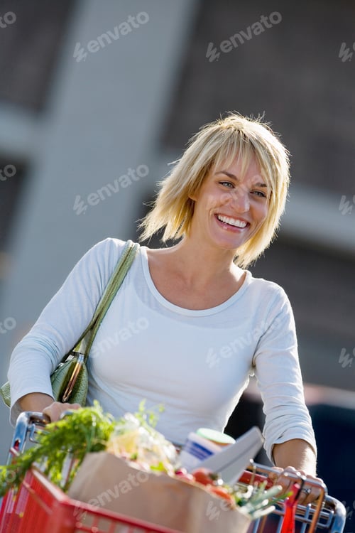 Preview: Smiling Woman Pushing Shopping Trolley In Supermarket Car Park