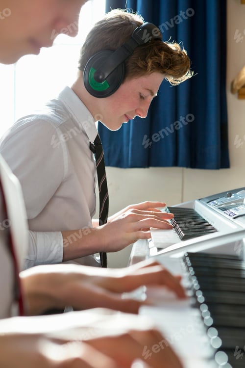 Preview: Vertical Shot Of Male High School Student With Headphones Playing Piano In A Music Class.