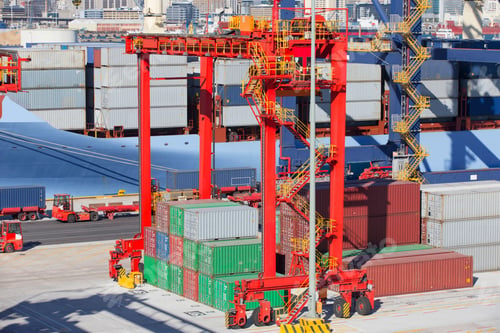 Preview: Cranes And Stacked Cargo Containers Next To A Container Ship At A Commercial Dock.
