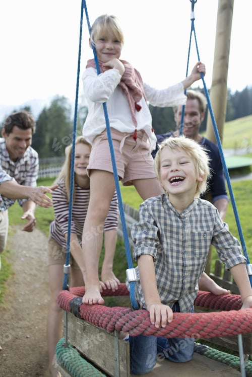 Preview: Father Pushing Children On Swing In Adventure Playground