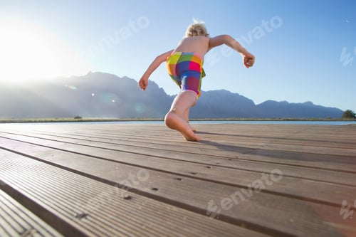 Preview: Low-Angle Shot Of A Boy Standing On A Wooden Jetty And Jumping Into The Lake.