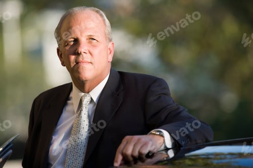 Preview: Portrait Of Mature Businessman By Car At Camera