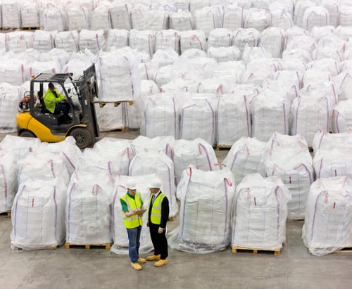 Preview: Businessman And Workers Among Large Bags Of Recycled Plastic Pellets In Warehouse And A Worker