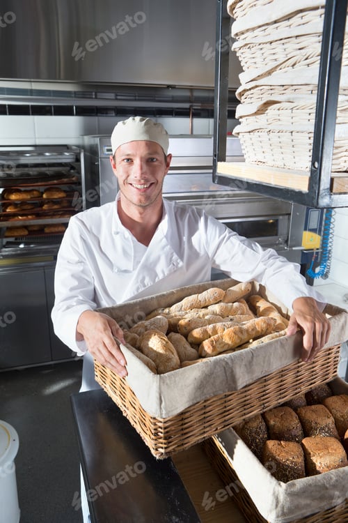 Preview: Smiling Baker Holding A Basket Of Breads In A Bakery Kitchen