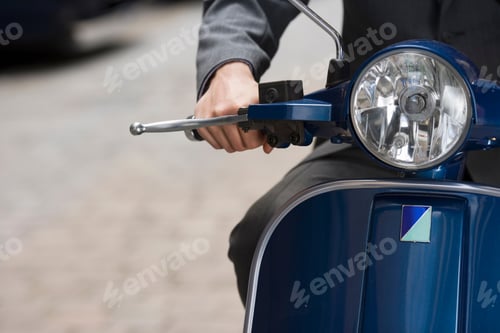 Preview: Close-Up Of Mid Section Of A Man Riding On Scooter In Street With Focus On Headlight.