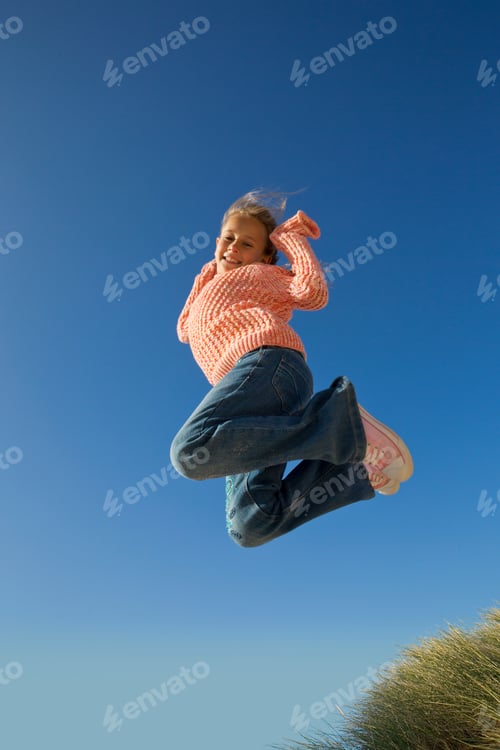 Preview: Low-Angle Vertical Shot Of A Girl Jumping Against The Blue Sky.