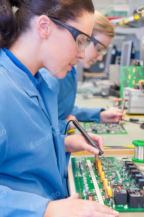 Preview: Close-Up Shot Of Technicians Wearing Safety Glasses As They Solder Circuit Boards In A