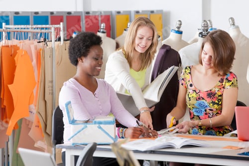 Preview: Young Fashion Design Students Working Together In A Classroom With Mannequins In The Background.