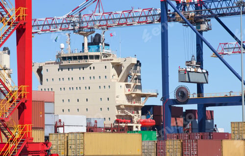 Preview: Crane Unloading Cargo Containers At A Commercial Dockyard With A Ship In The Background.