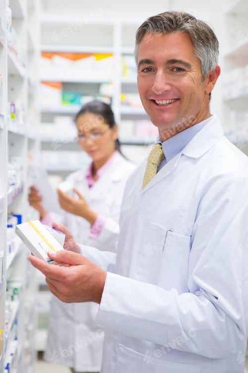 Preview: Portrait Shot Of A Male Pharmacist Smiling At The Camera While Going Through Medicine Boxes At A