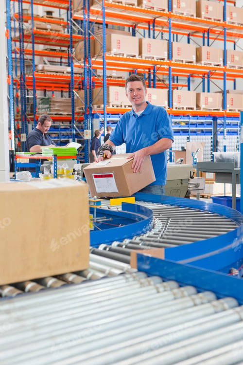 Preview: Vertical Wide Shot Of A Worker Smiling At The Camera While Scanning A Cardboard Box On The