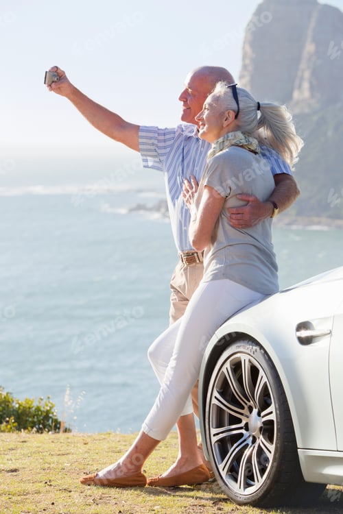 Preview: Vertical Portrait Of A Senior Couple Taking A Selfie Hugging Each Other Leaning Against The Car