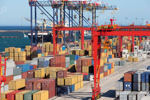 Preview: Wide Shot Of Cranes And Stacked Cargo Containers At A Commercial Dock With A Container Ship In The