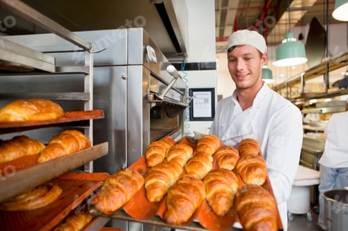 Preview: Smiling Baker Placing Freshly Baked Breads In The Rack